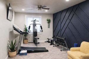 Modernt hemmagym med löpband, hantlar och gymmaskin framför en mörk fondvägg.